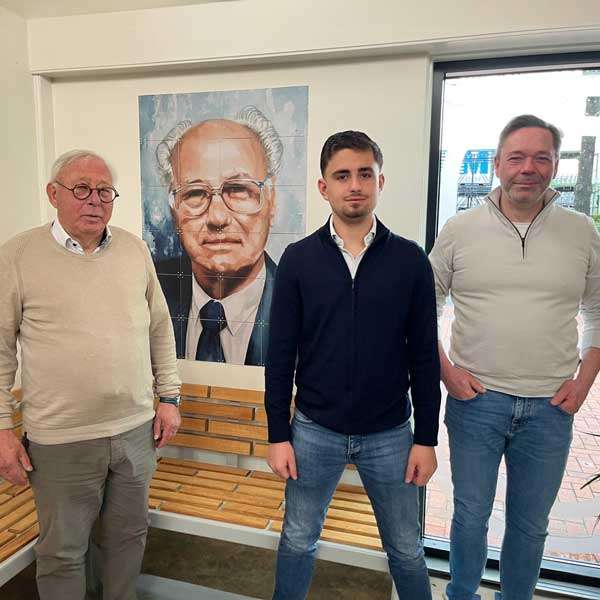 Foto van Gerrit, Franz en Jirayr Friesacher bij een portret van oprichter Franz sr., symbool voor de familietraditie en continuïteit van Falco. Foto van Gerrit, Franz en Jirayr Friesacher bij een portret van oprichter Franz sr., symbool voor de familietraditie en continuïteit van Falco.
