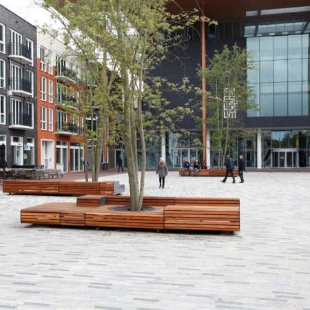 Levendig plein met zitelementen en boombescherming ineen
