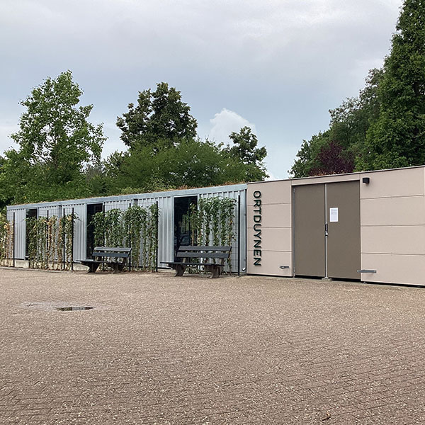Grote overkapping in gebruik als fietsenstalling en containerberging bij appartementencomplex