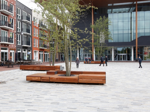 Levendig plein met zitelementen en boombescherming ineen